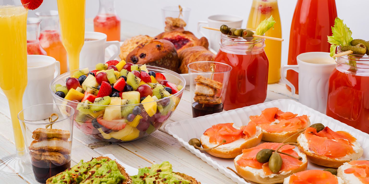 Plates full of various foods and fruits along with drinks presented on a table